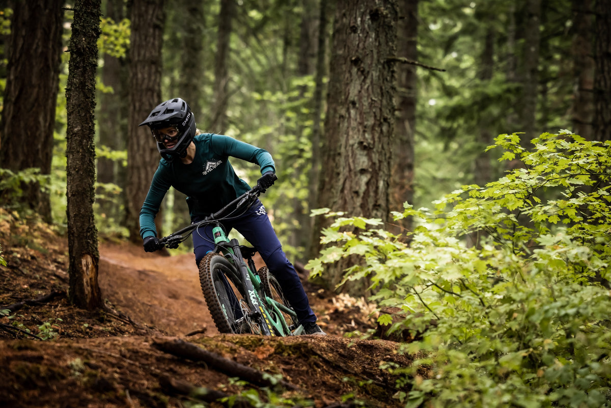 Mountain biker riding a forest trail in Revel Rider apparel