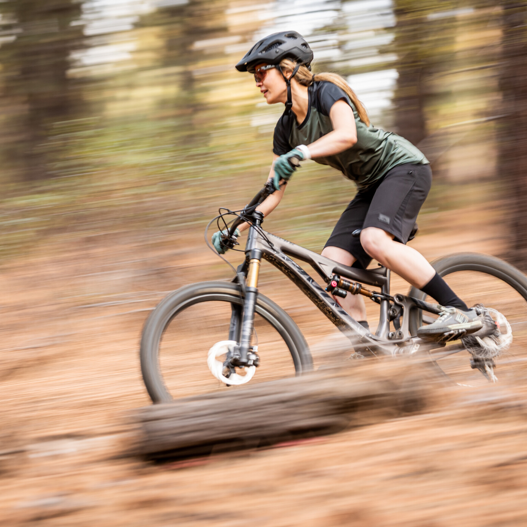 Mountain biker wearing the Black/Green RIDE Short Sleeve Jersey on a forest trail